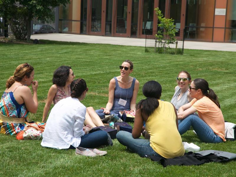 7 women seated in a circle on the grass