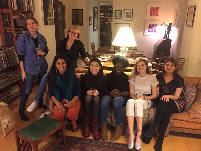 5 young women seated on a couch, 2 older women st和ing nearby